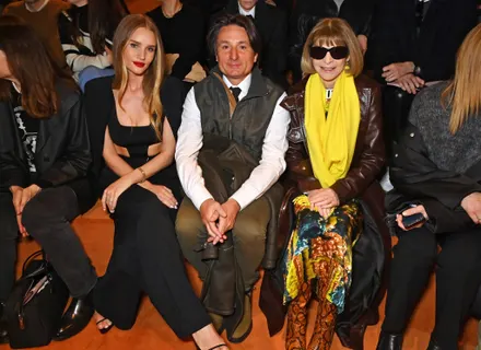 Three people posing at a fashion event, dressed stylishly.
