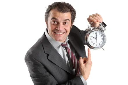 Man in suit excitedly holding a large clock.