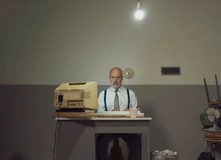Man sitting at desk with vintage computer.